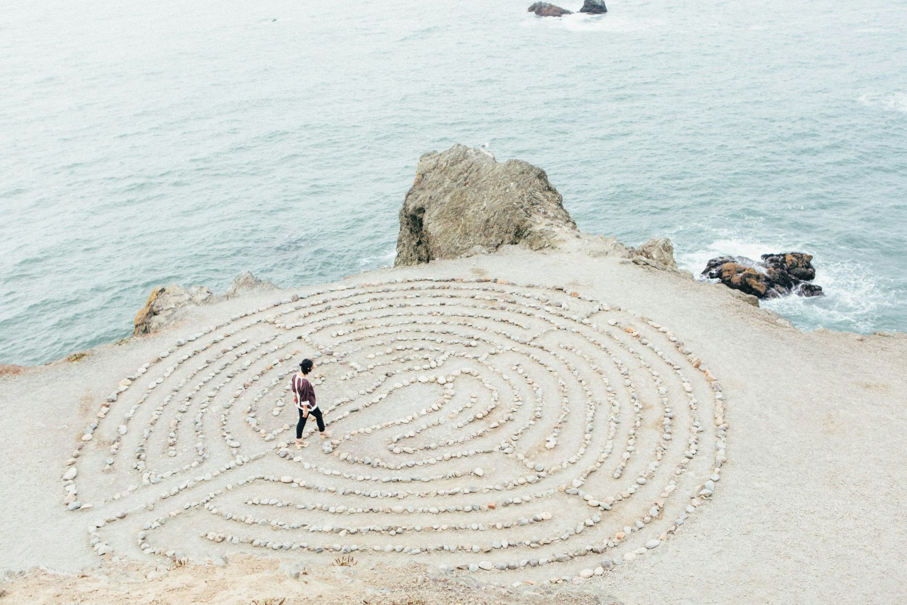 Person walking a stone labyrinth beside the sea
