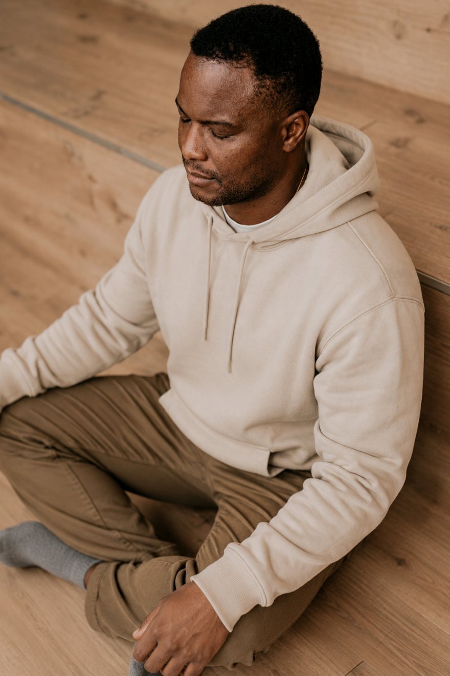 Man sitting cross-legged in quiet meditation on a wooden floor
